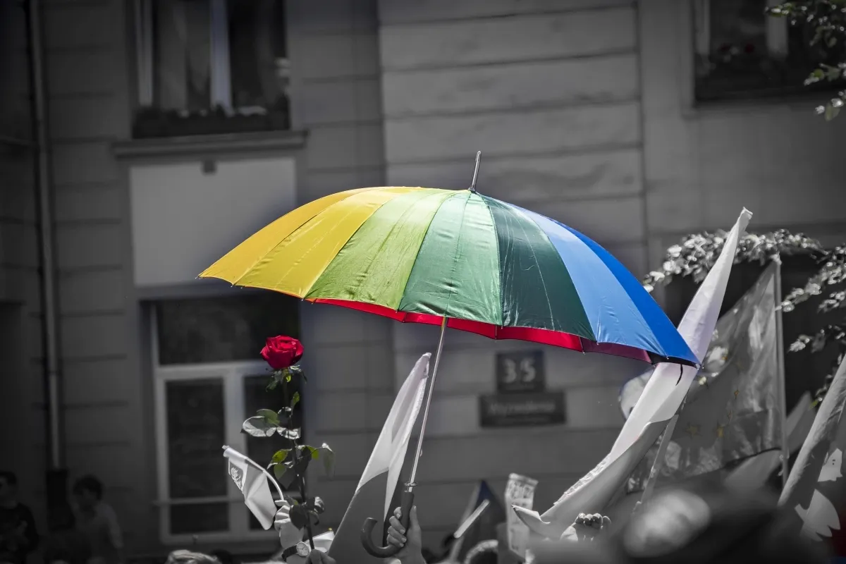Rainbow umbrella against a grayscale street scene